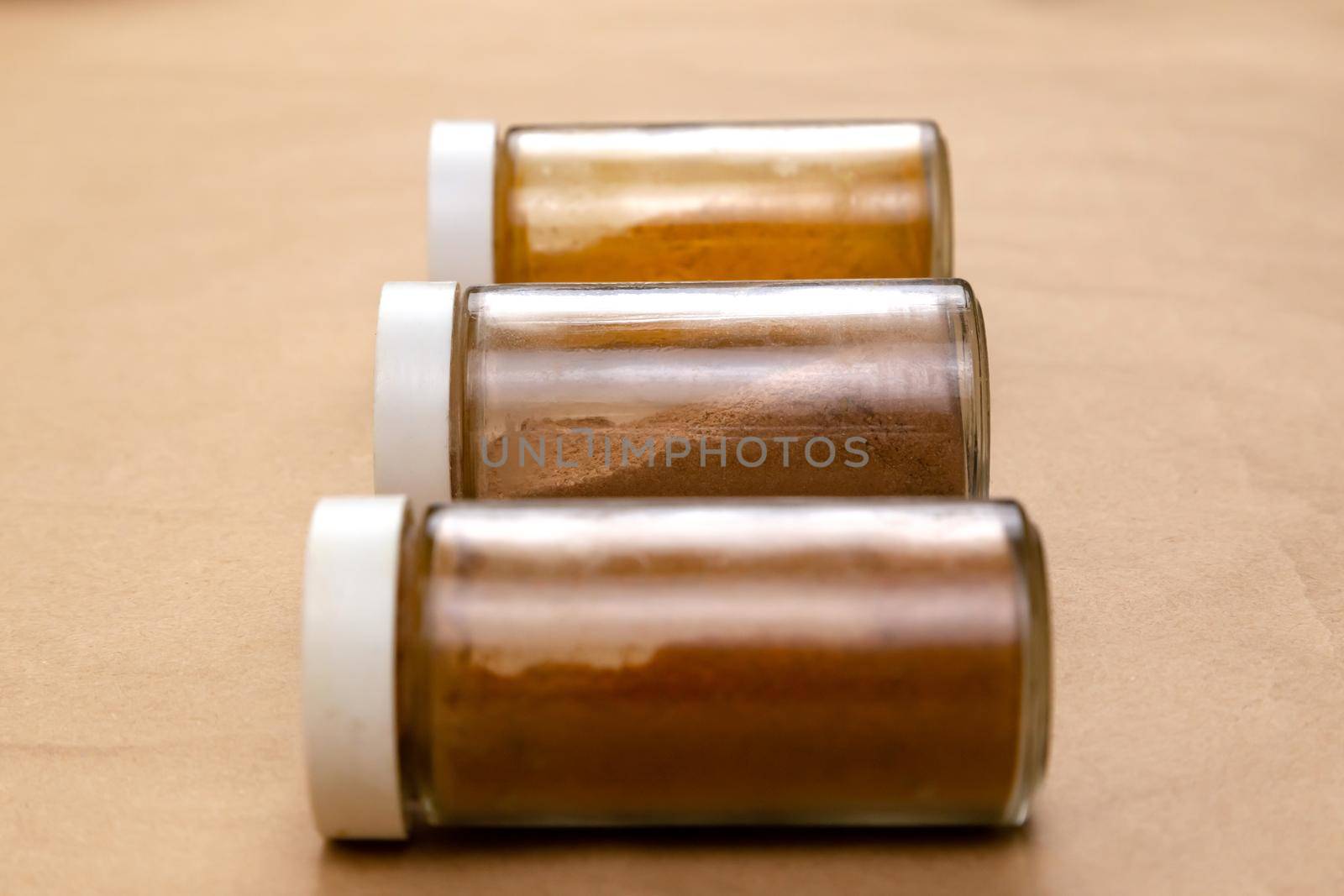 Three jars of seasoning on a brown background with selective focus