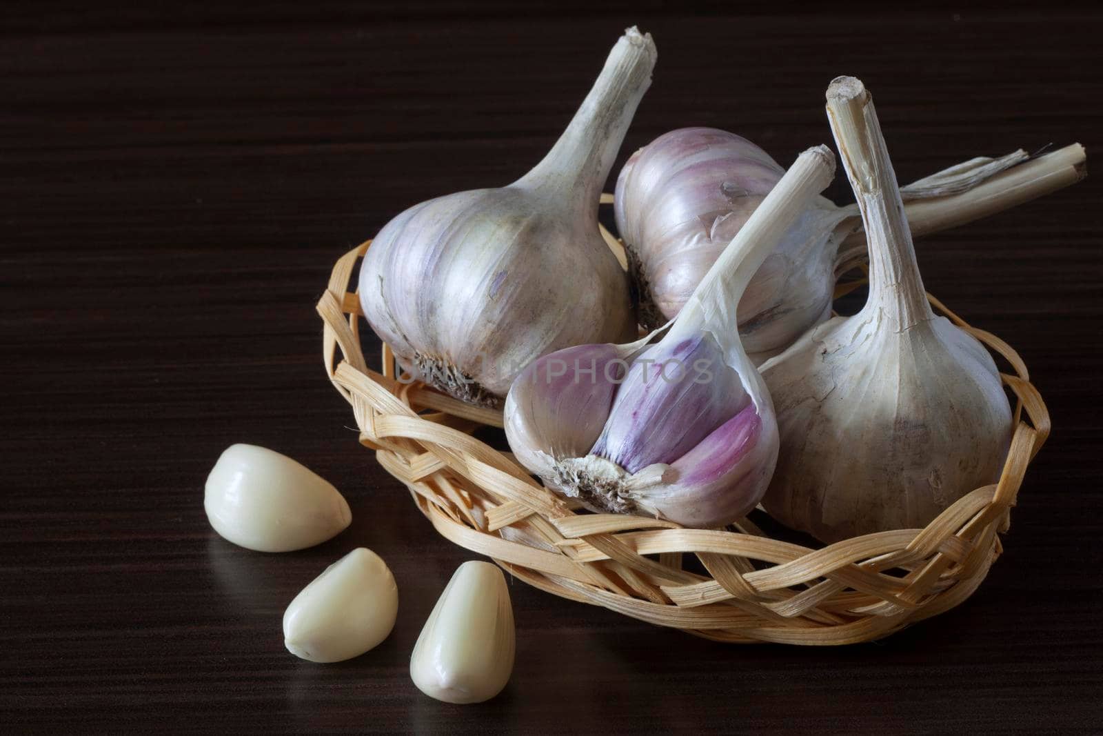 Garlic in a wicker vase on a dark background