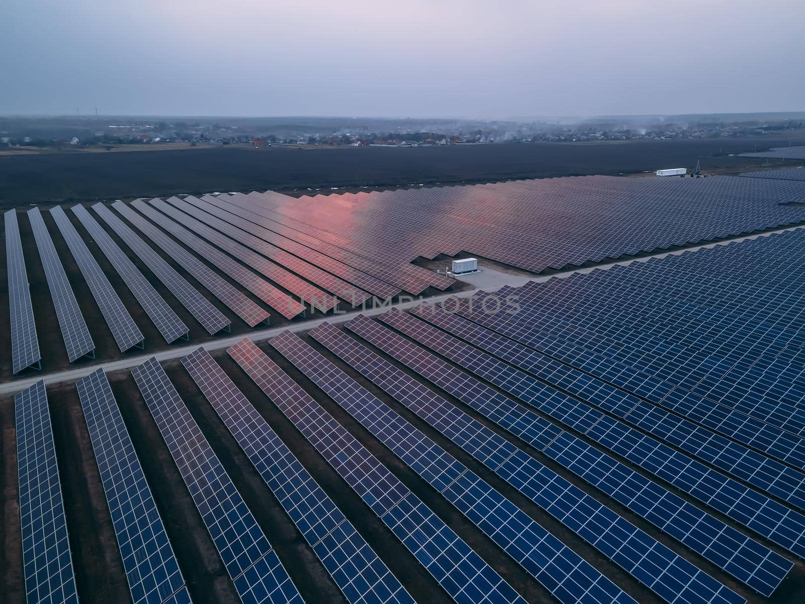 Aerial drone view of large solar panels at a solar farm at bright spring sunset. Solar cell power plants, colorful HDR photo