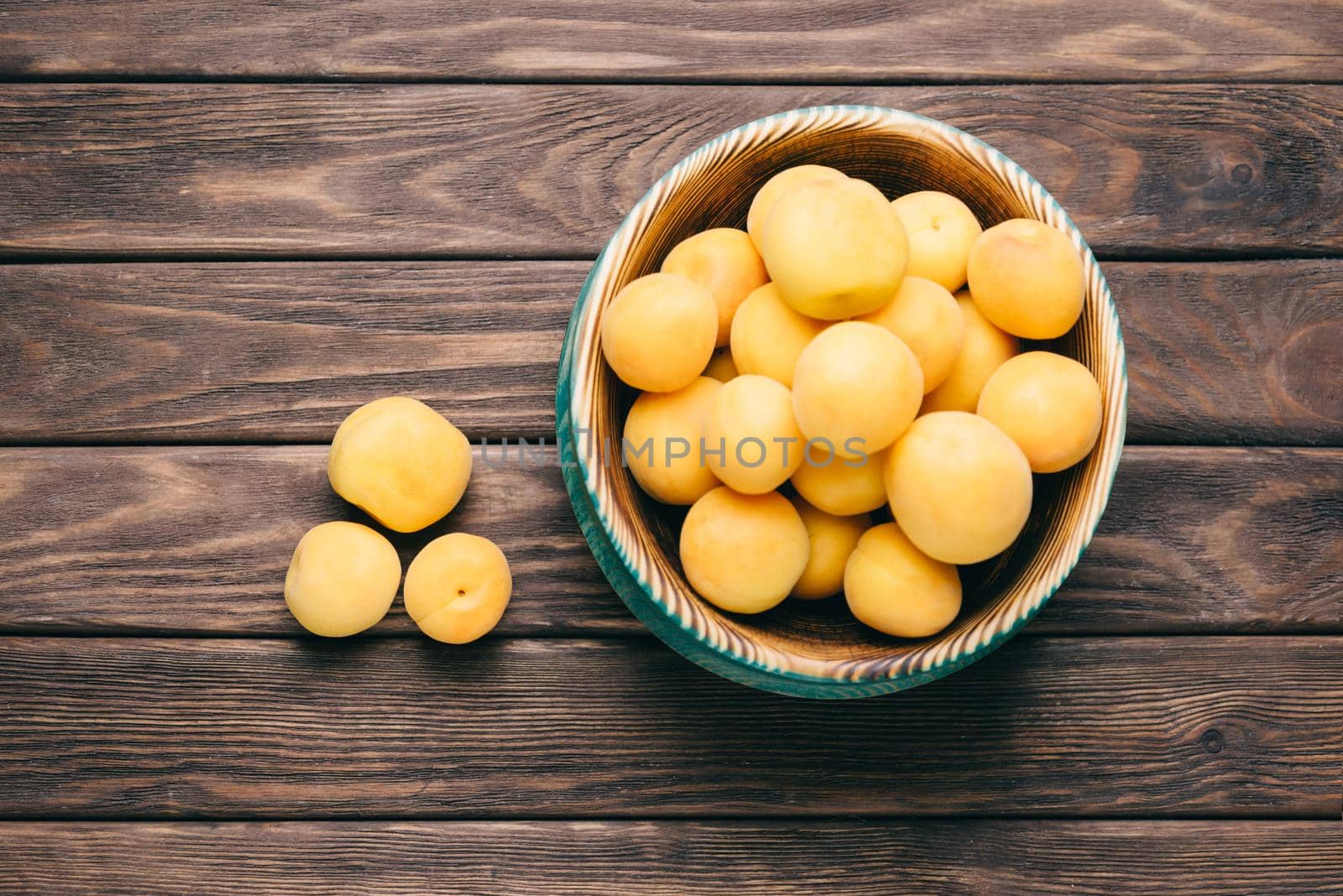 Fresh fruits apricots in a rustic bowl on a wooden table, top view.