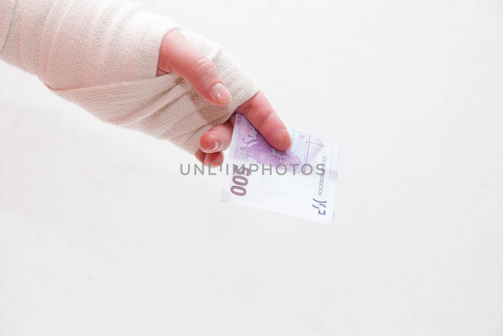 bandaged female hand holds a 500 euro bill