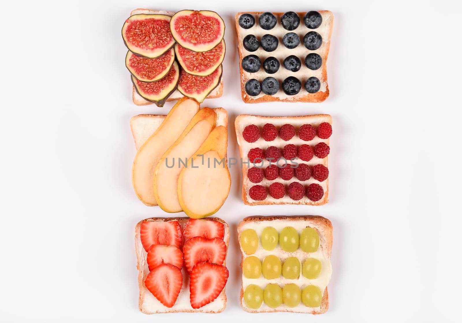 Set with toast and different vegan toppings isolated, top view. Toasts with pear, blueberries, raspberries, grapes, strawberries, figs and other fruit ingridients. Healthy snack concept. Copy space