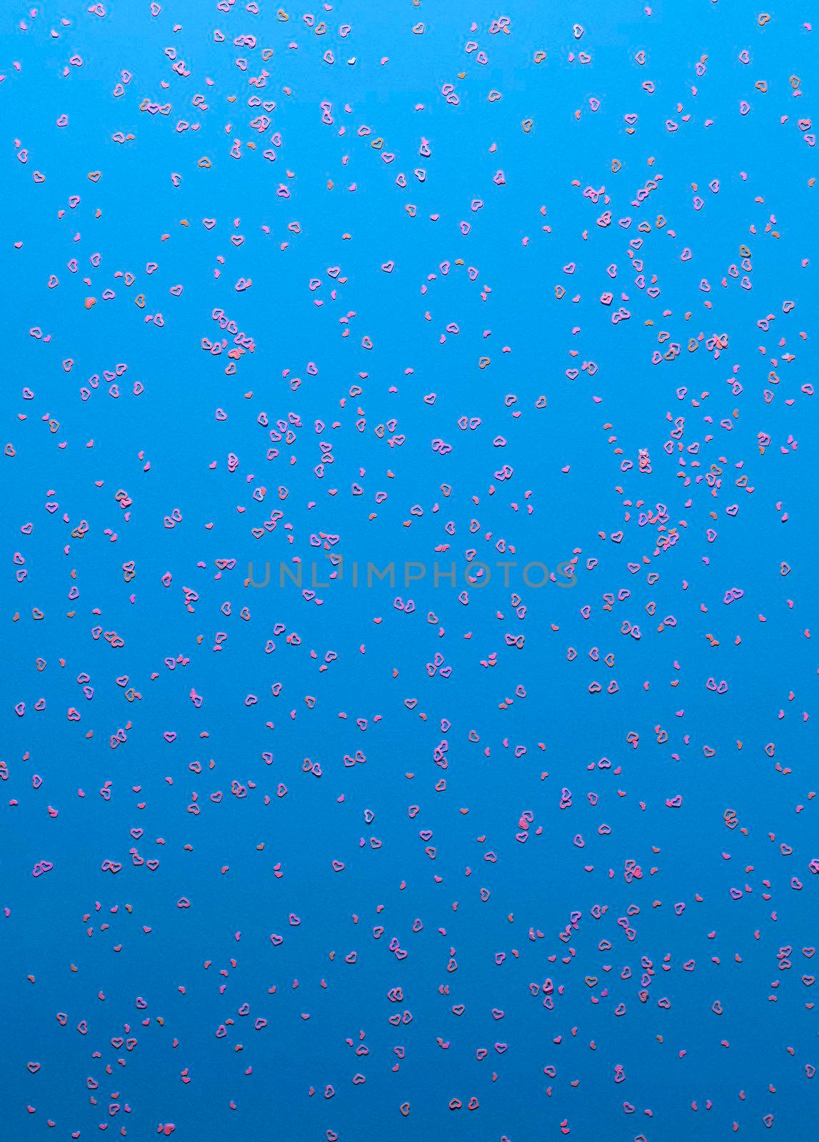 Neon pink sparkles in form of heart on blue background. Festive background for wallpaper, wrapping, backdrop, print or banner. Flat lay style.