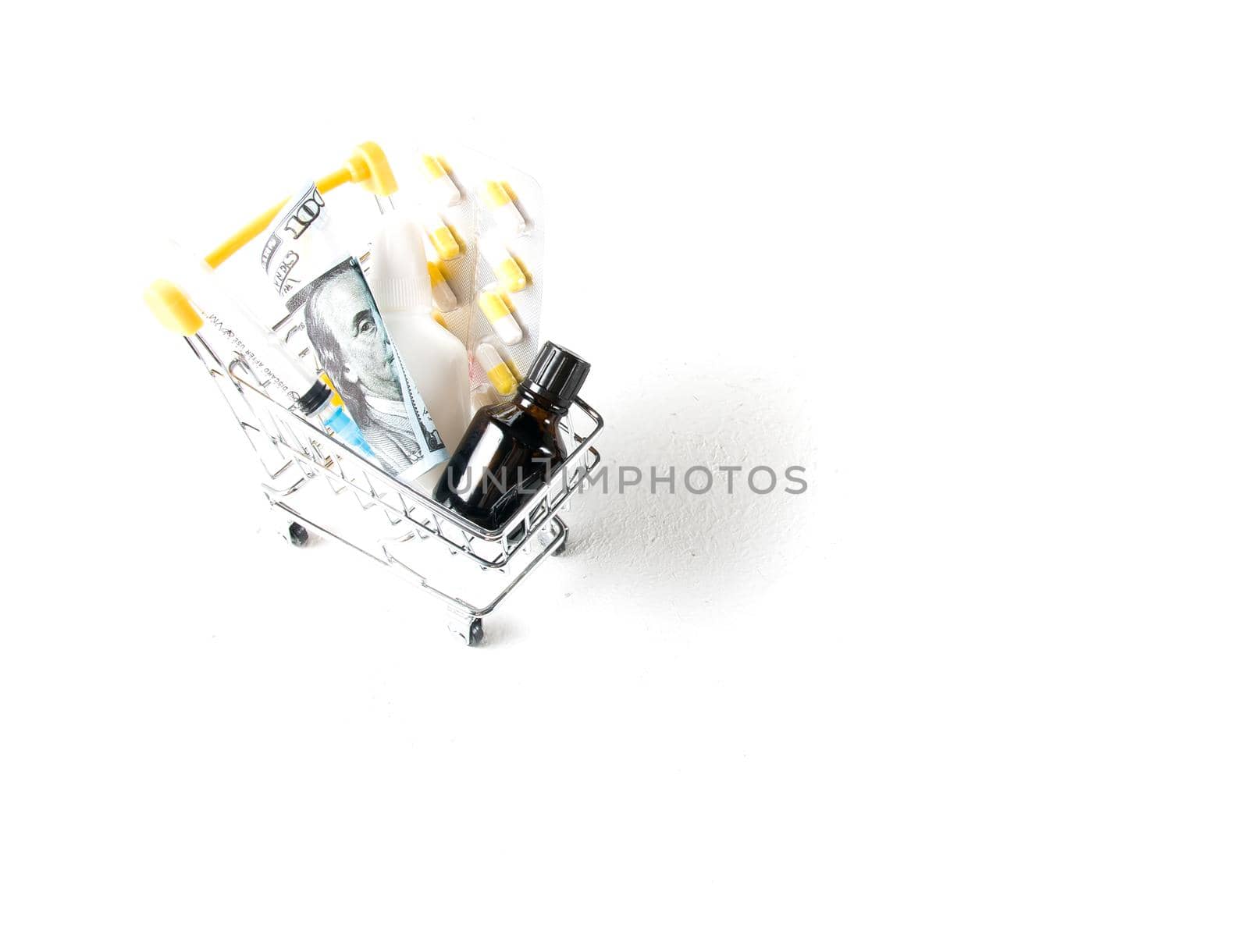 medicines in a shopping trolley and 500 euro bills on a white background copy space by natashko