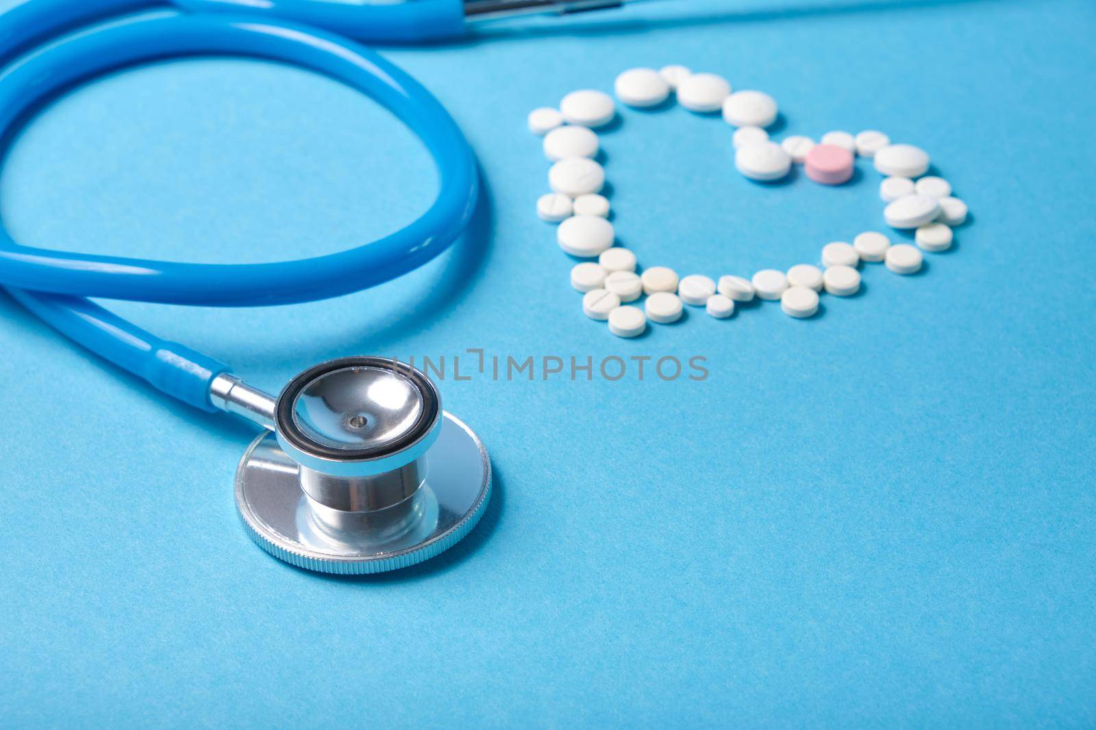 stethoscope and heart from pills on blue background, cardiology concept by natashko