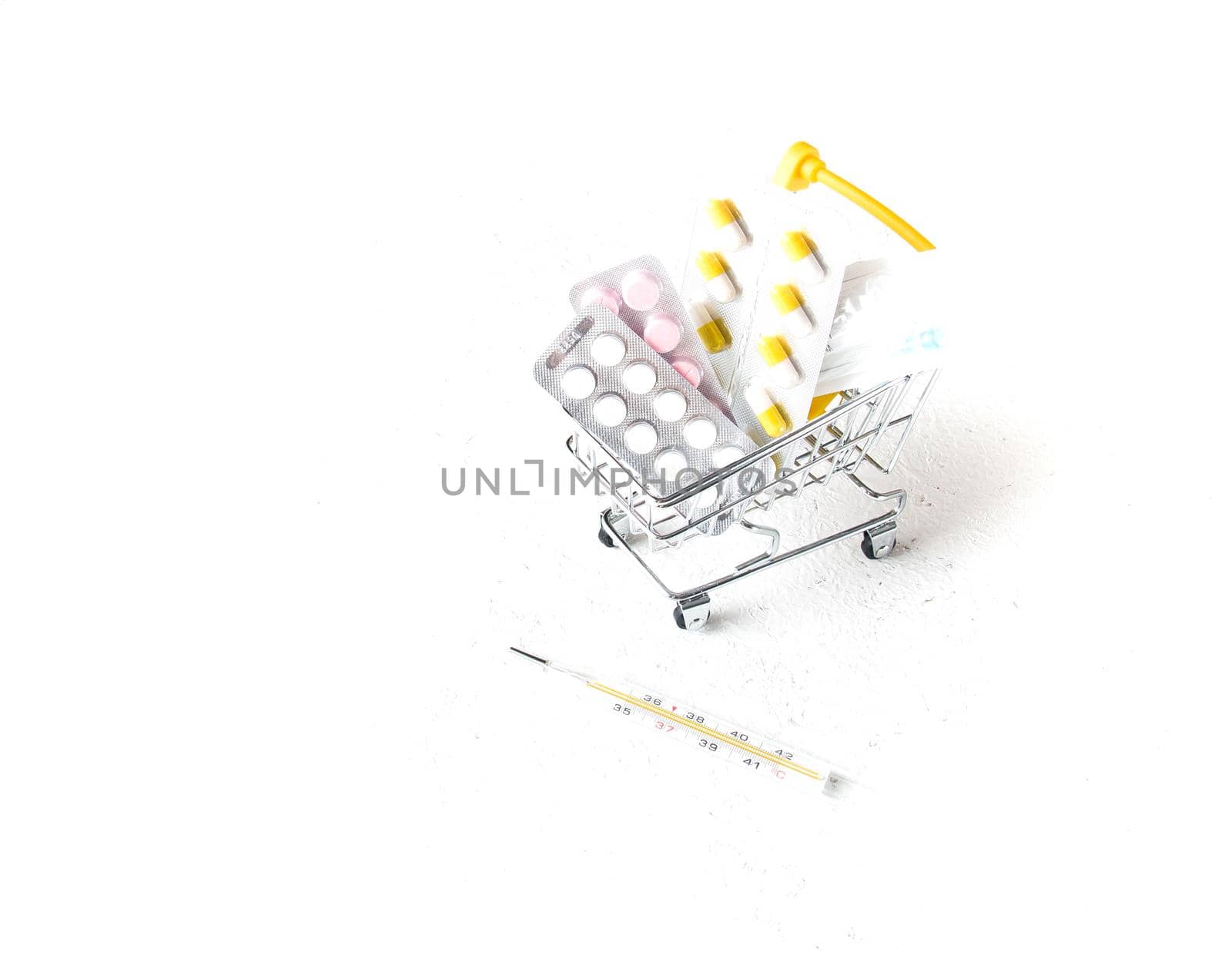 syringe, pills in a shopping trolley and mercury thermometer on a white background copy space