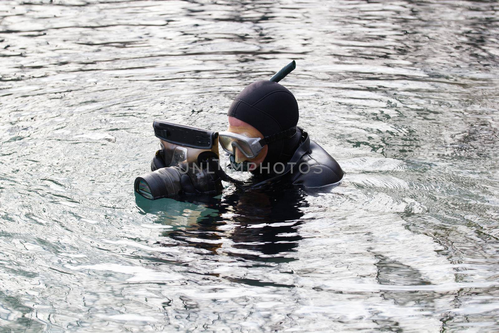 fisherman in wetsuit with photo camera in hands in preparation for a photohunt. Portrait