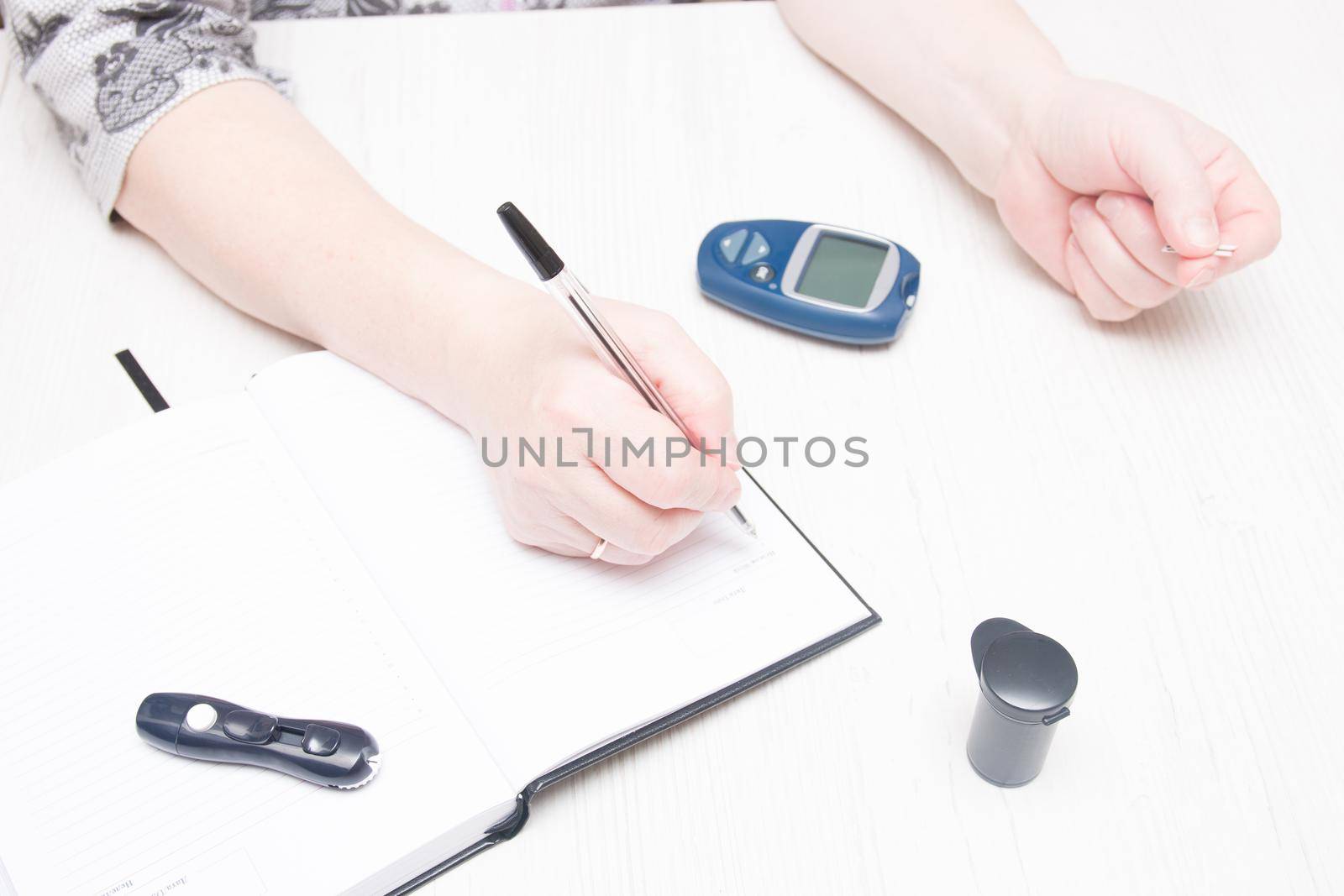 woman holds a pen to record the results of a glucose test, diabetes concept, blood sugar control