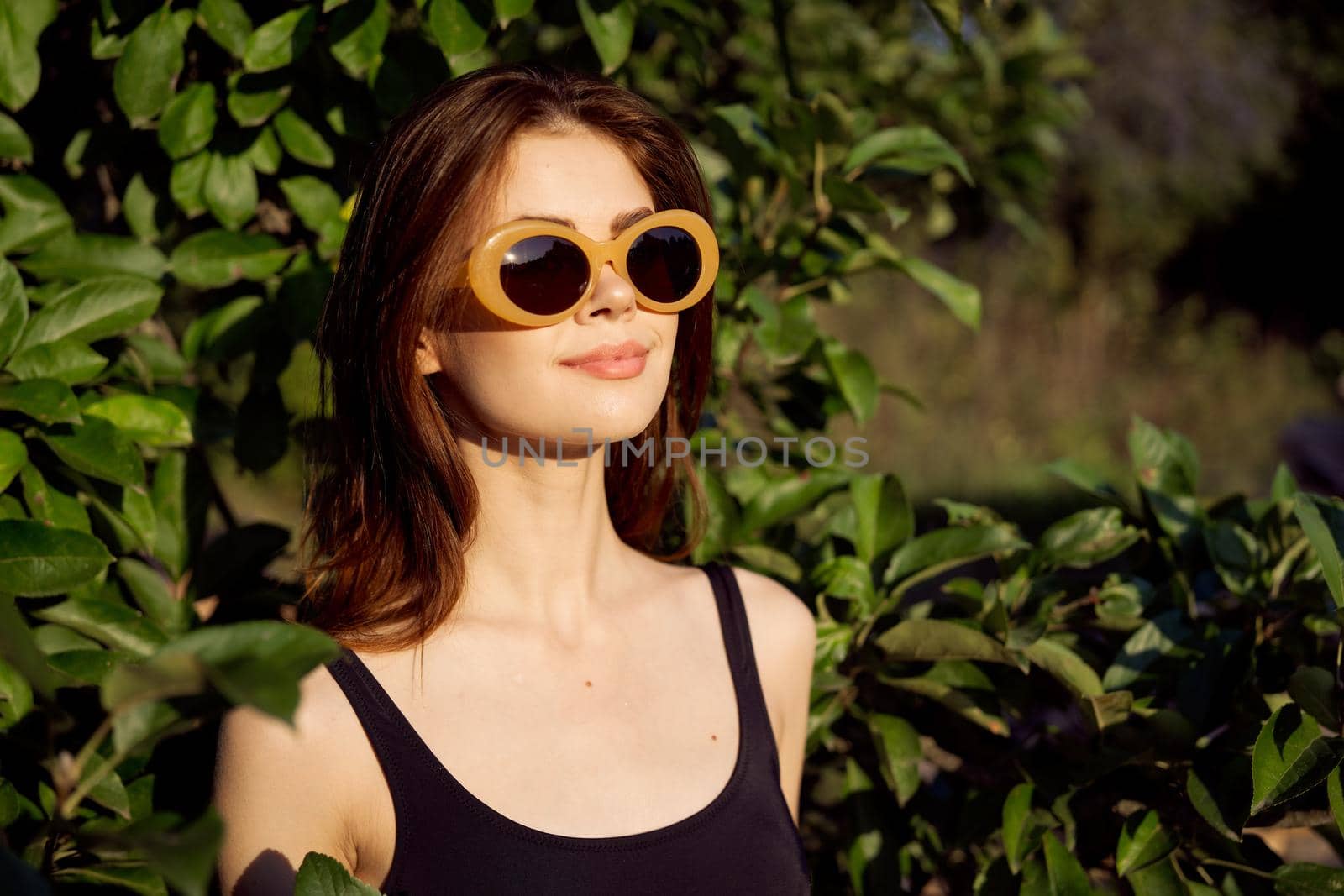 pretty woman in black swimsuit sunglasses green leaves nature. High quality photo