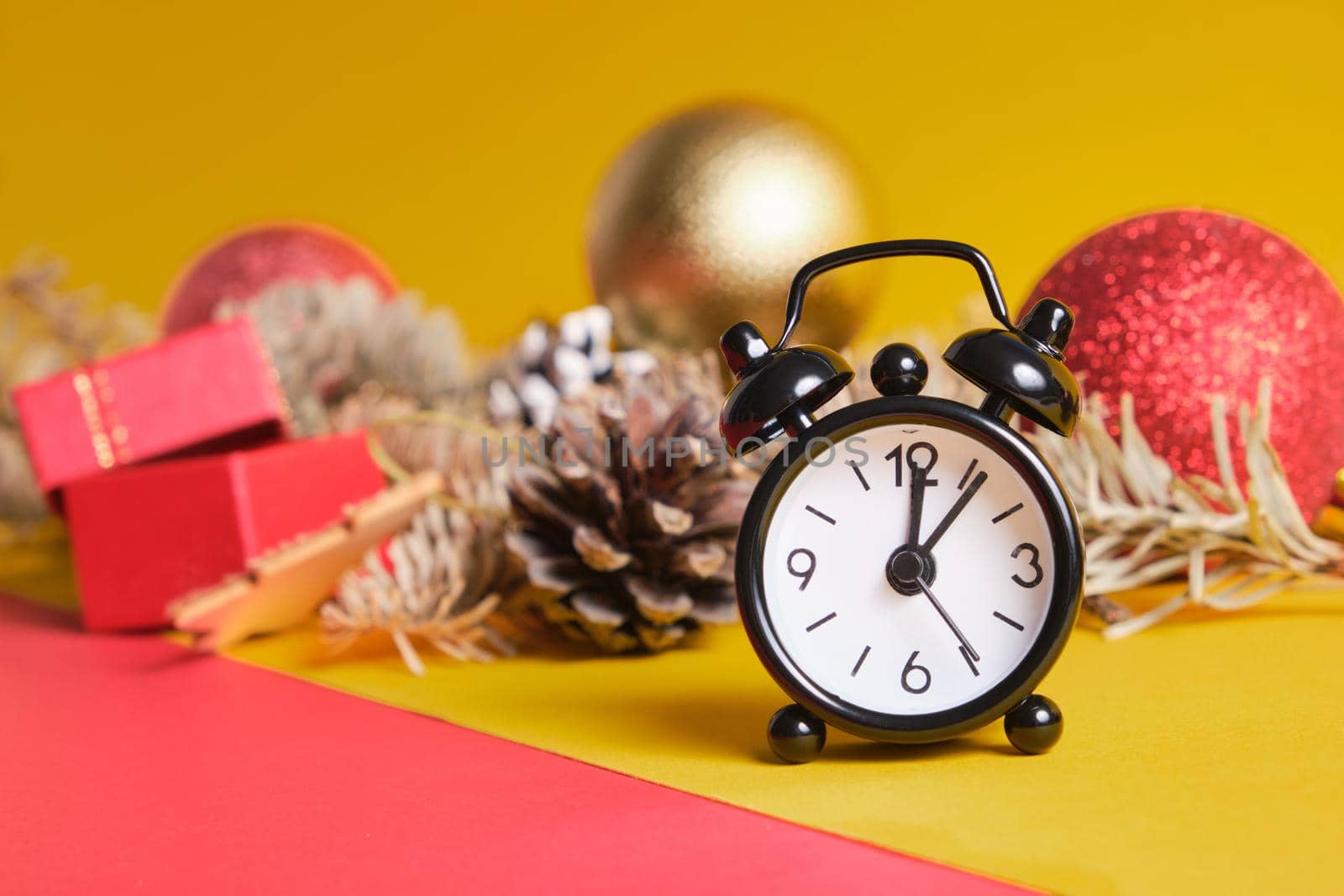 black small alarm clock and christmas decor on yellow background