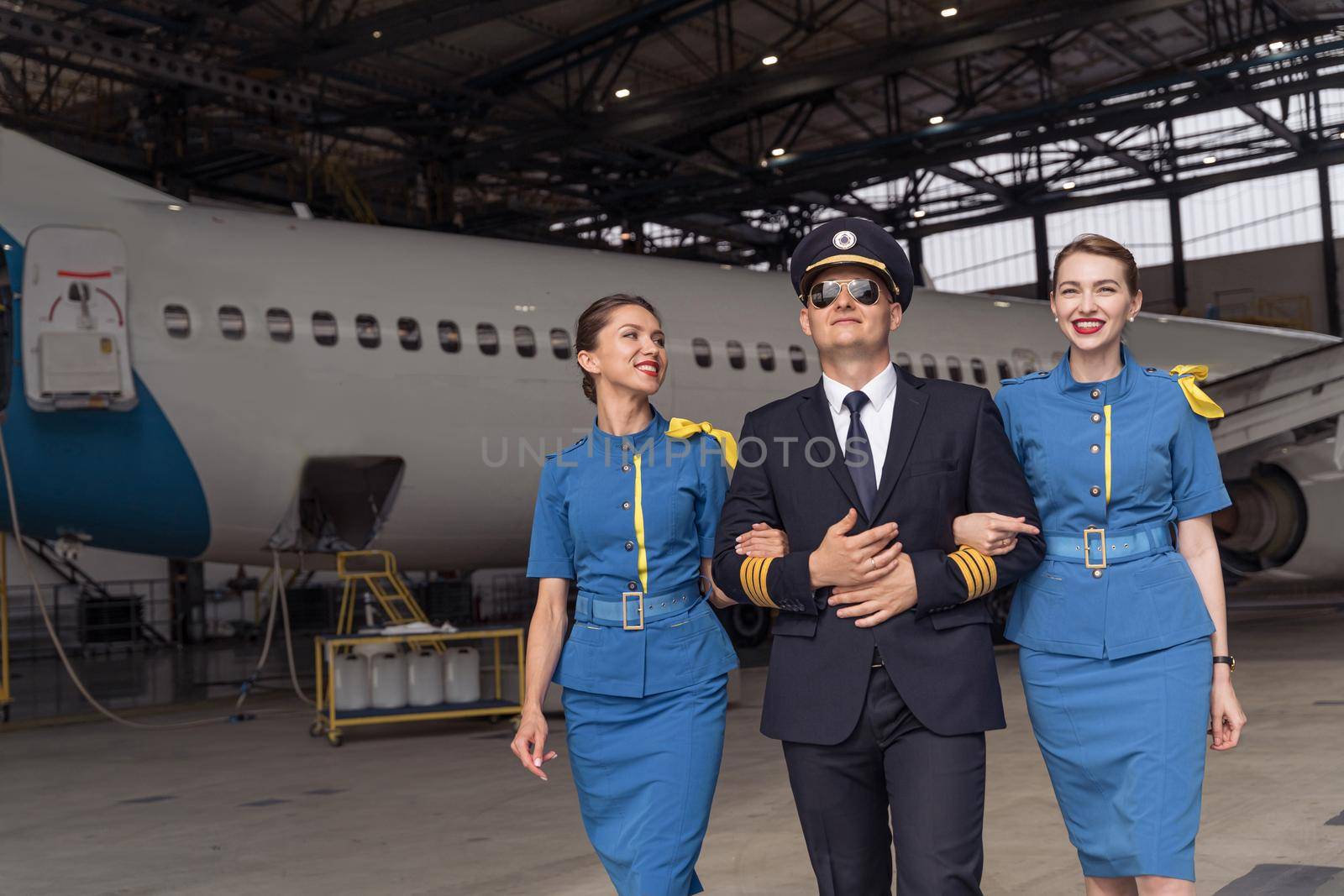 Pilot and flight attendants walking through the hangar together by Yaroslav_astakhov