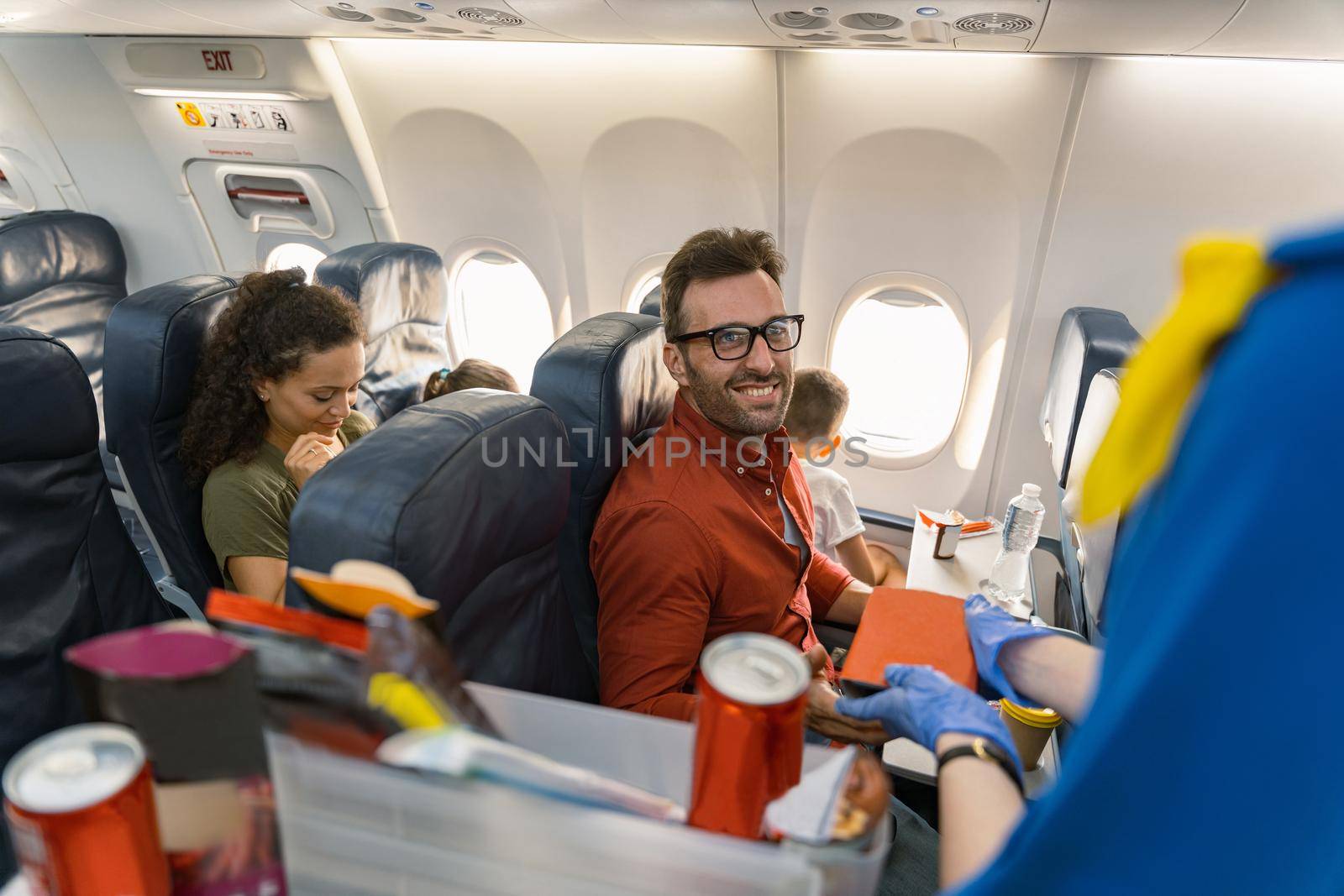 Smiling adult man looking at the stewardess while waiting for lunch on board while traveling with family