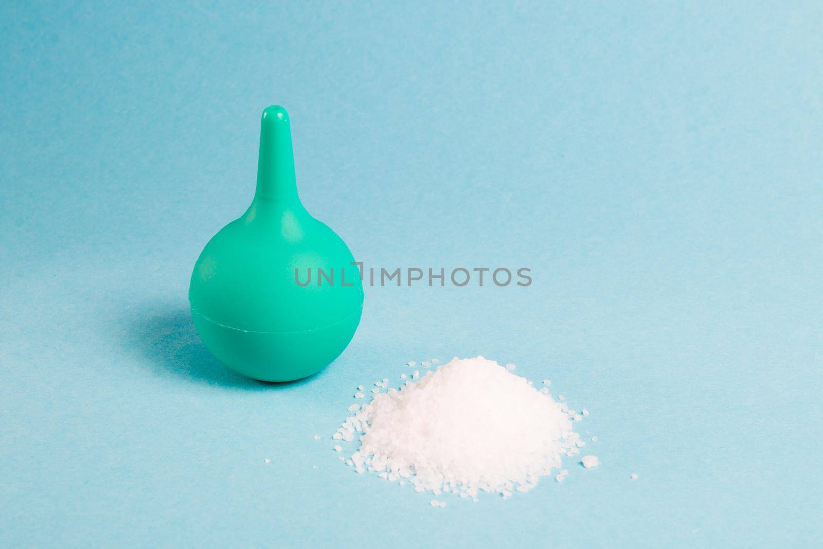 enema for the nose and a wooden spoon with sea salt on a light blue background, copy space, washing the nose with salt water using an aspirator by natashko