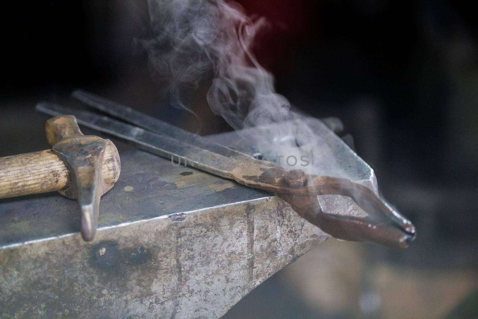 steam comes from the different tools lies on anvil. Close up shot