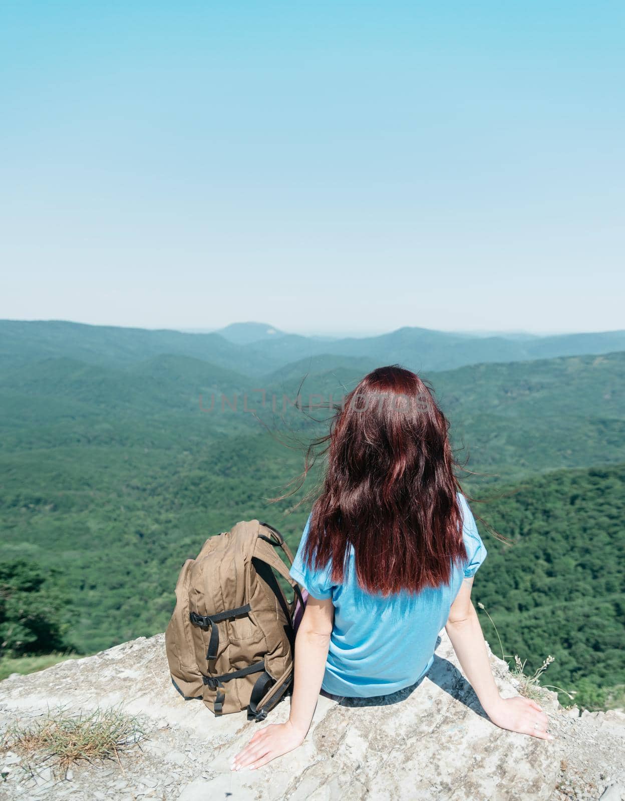 Backpacker woman sitting on peak of cliff in summer. by alexAleksei