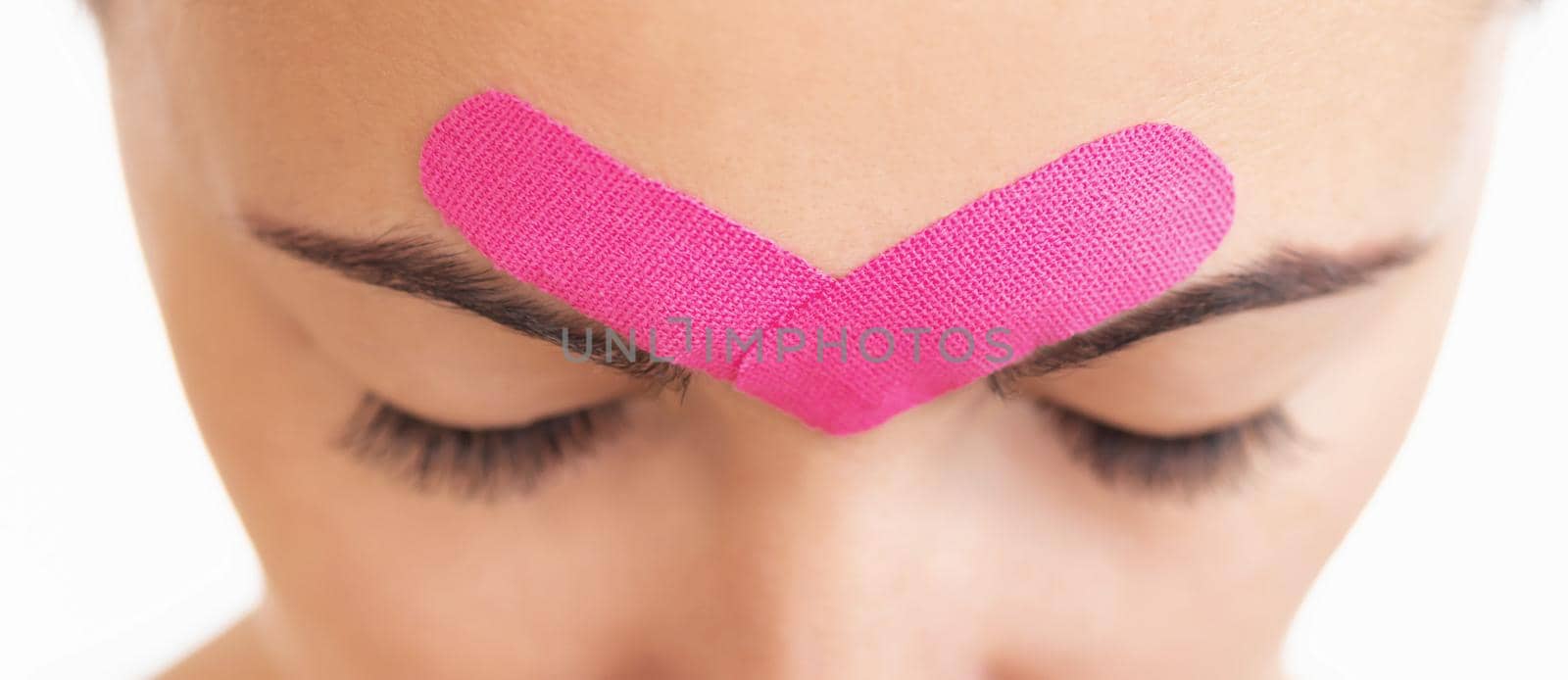 Woman with kinesio tape over eyebrows. by alexAleksei