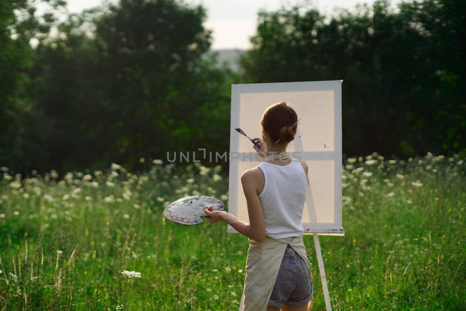 woman artist outdoors with palette of paints paints a picture by Vichizh