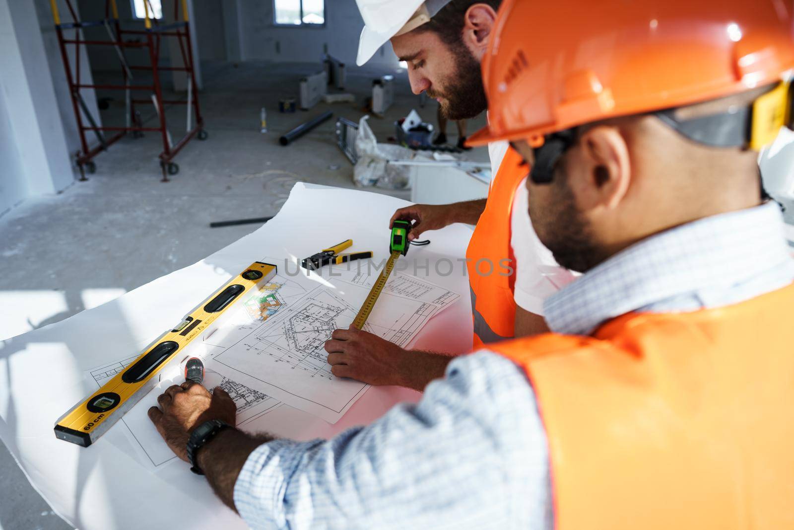 Two young engineers man looking at project plan on the table in construction site