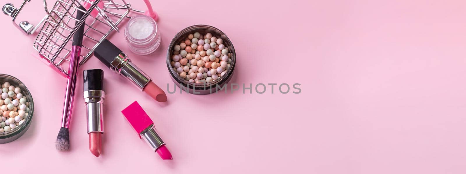 Creative concept with shopping trolley with makeup on a pink background. Makeup brushes, lipsticks,lip gloss in the basket, copy space.Cosmetics in the shopping cart.Bkack friday concept. by YuliaYaspe1979