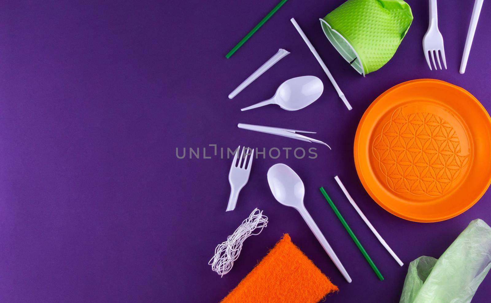 Single-use plastic objects, ecological pollution. Plastic waste. Orange, white and green packaging plastic products, top view flat lay border frame with copy-space.