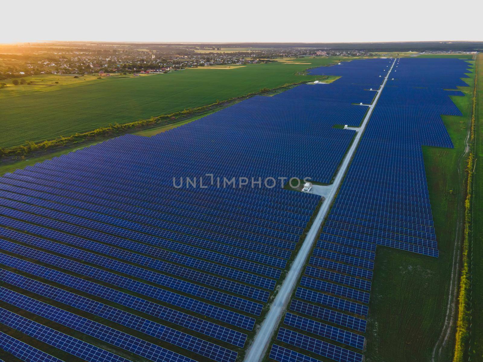 Aerial drone view of large solar panels at a solar farm at bright summer sunset. Solar cell power plants, colorful photo