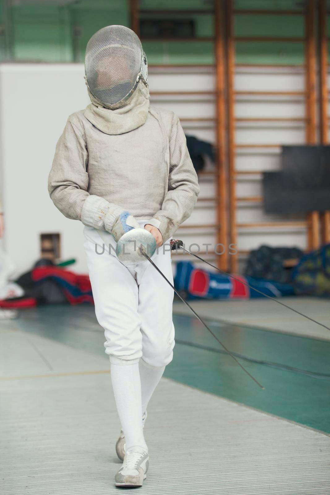 Young fencer in special costume at the fencing competition with rapier, telephoto shot