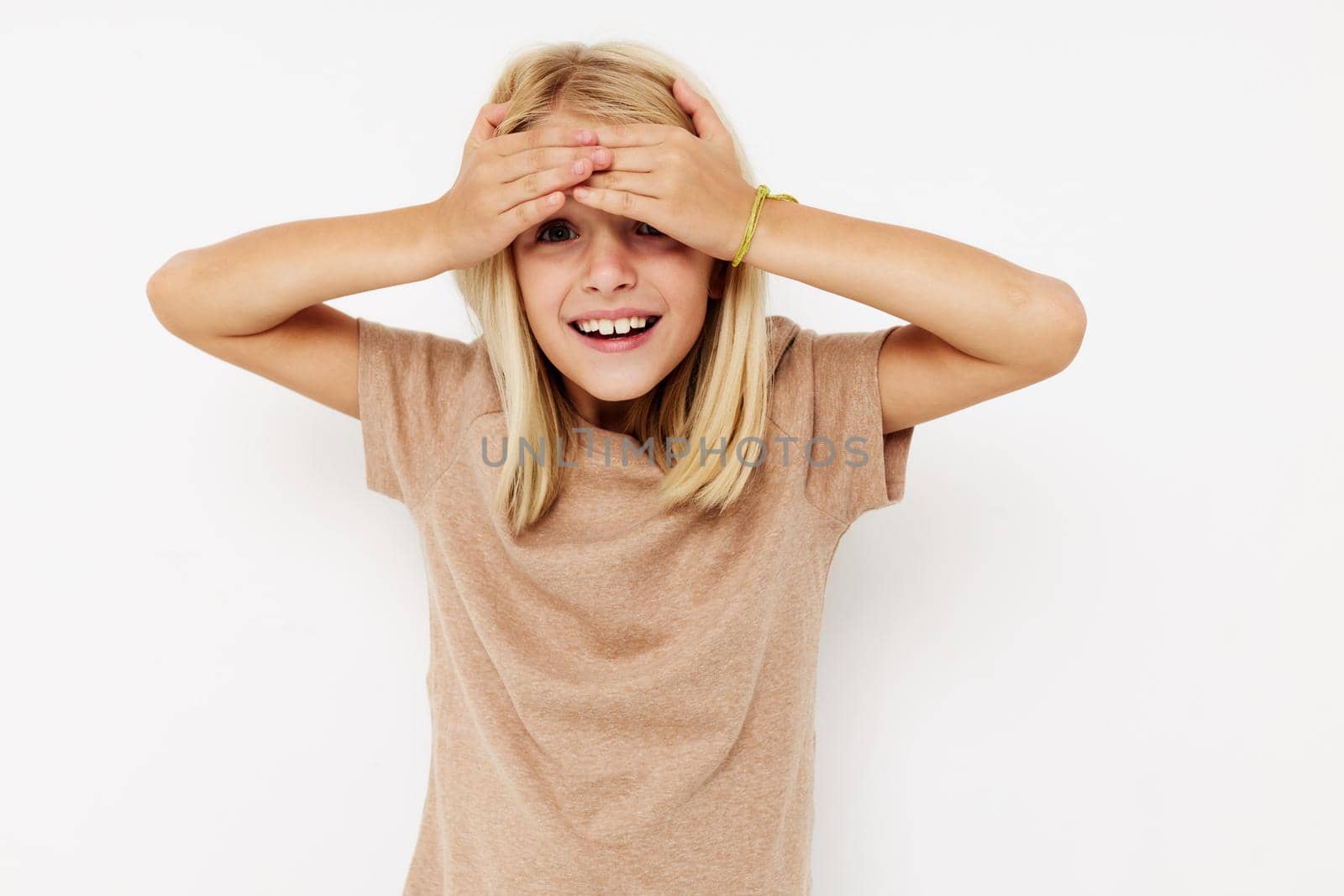 Portrait of a smiling little cutie in a beige t-shirt posing studio by SHOTPRIME