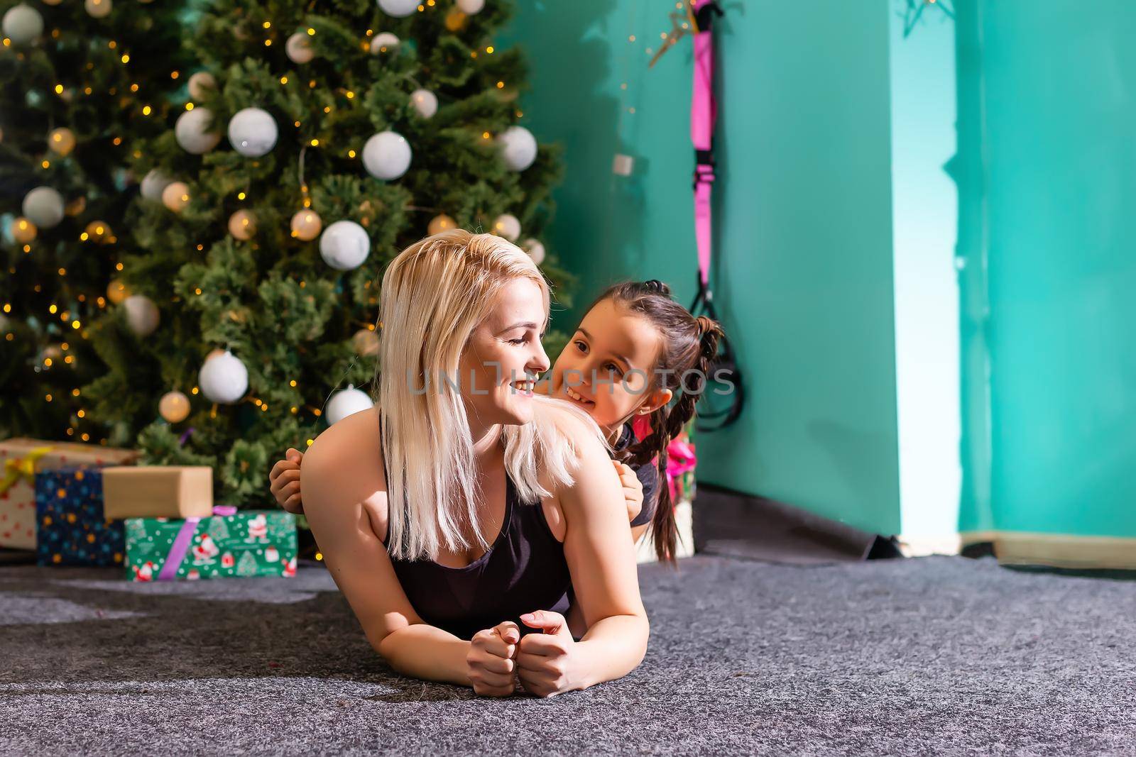 active mother and daughter doing fitness near the christmas tree