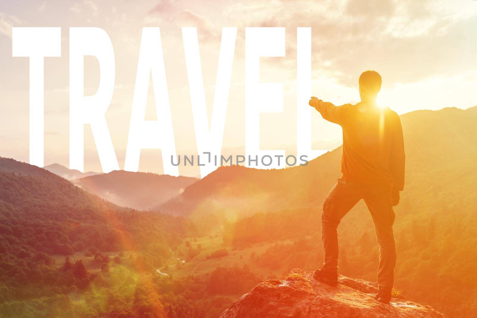 Explorer young man pointing at word travel in summer mountains at sunset.