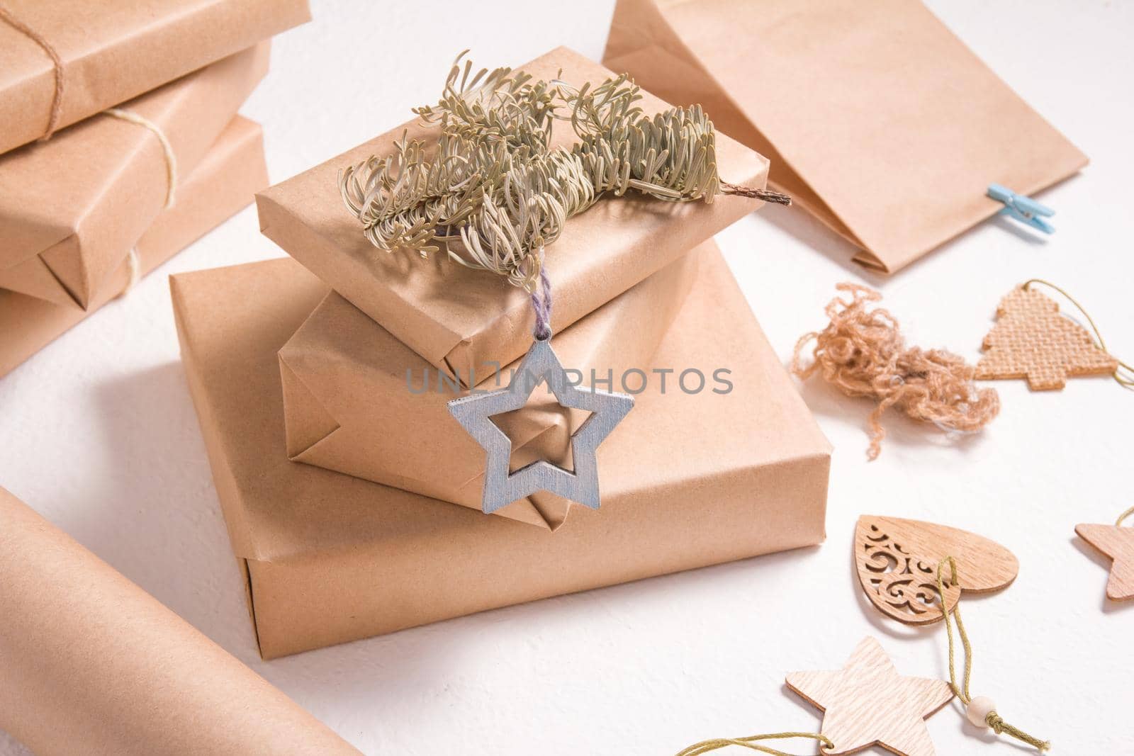eco style christmas gift wrappers, some gift boxes decorated with wooden christmas tree toys, dry spruce branch, white background, zero waste lifestyle