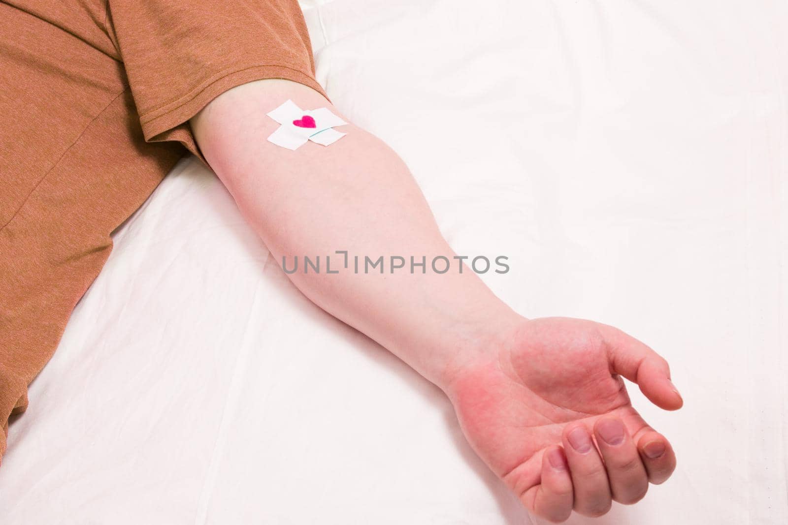 male hand with patch glued with a cross, heart on a patch, blood donor concept by natashko