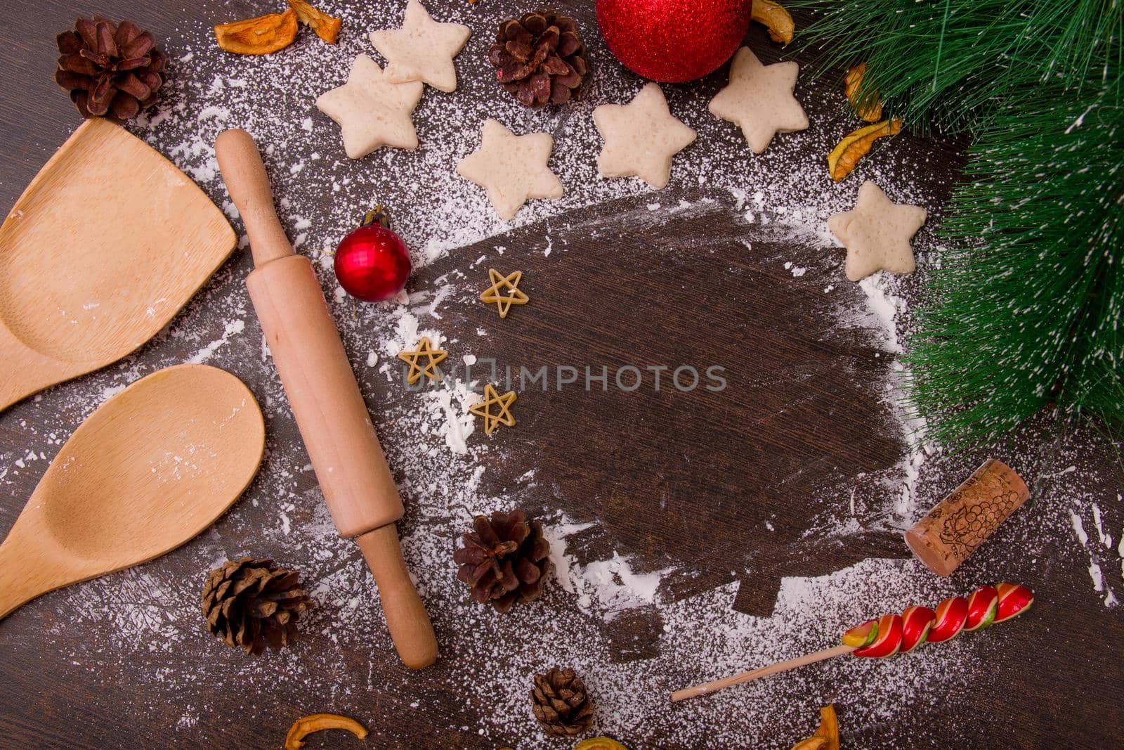 bake pastry cookies, star-cookies, wooden kitchen utensils, shovels, rolling pin, flour scattered on a brown wooden table, pine artificial branch, Christmas decorations, New Year, Christmas, holiday cooking