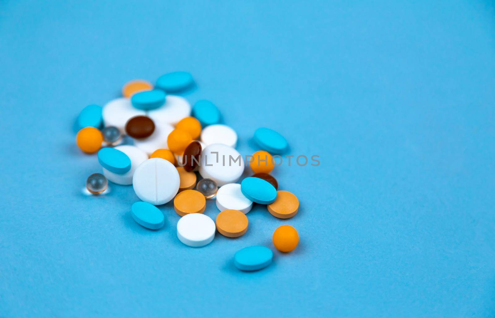 Multi-colored pills on a blue background close-up, with copy space for text by lunarts