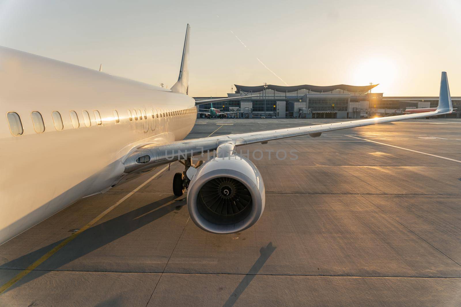 Cropped photo of big white airplane parked at the airport at sunset. Transport concept