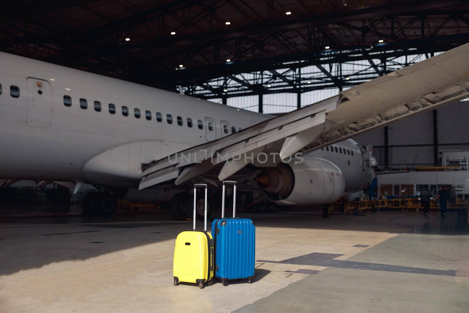 Two colorful suitcases of air stewardesses in empty airport hangar on a sunny day. Occupation, departure, journey concept