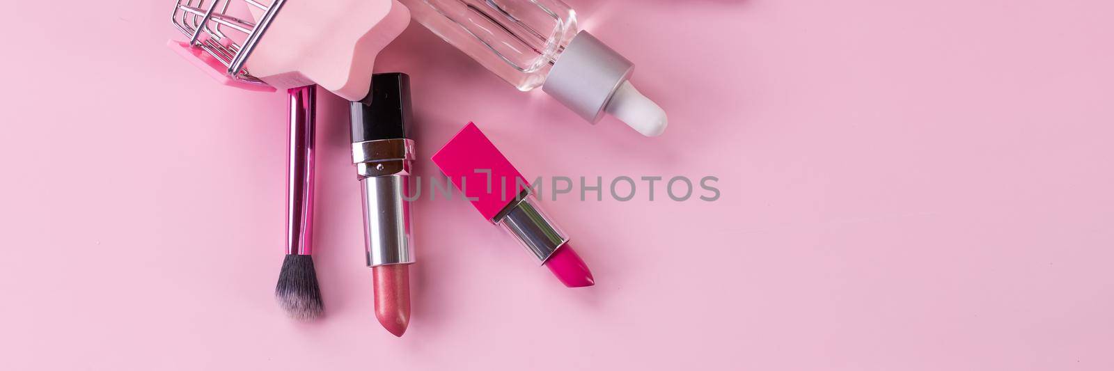 Shopping trolley with make-up products over white background