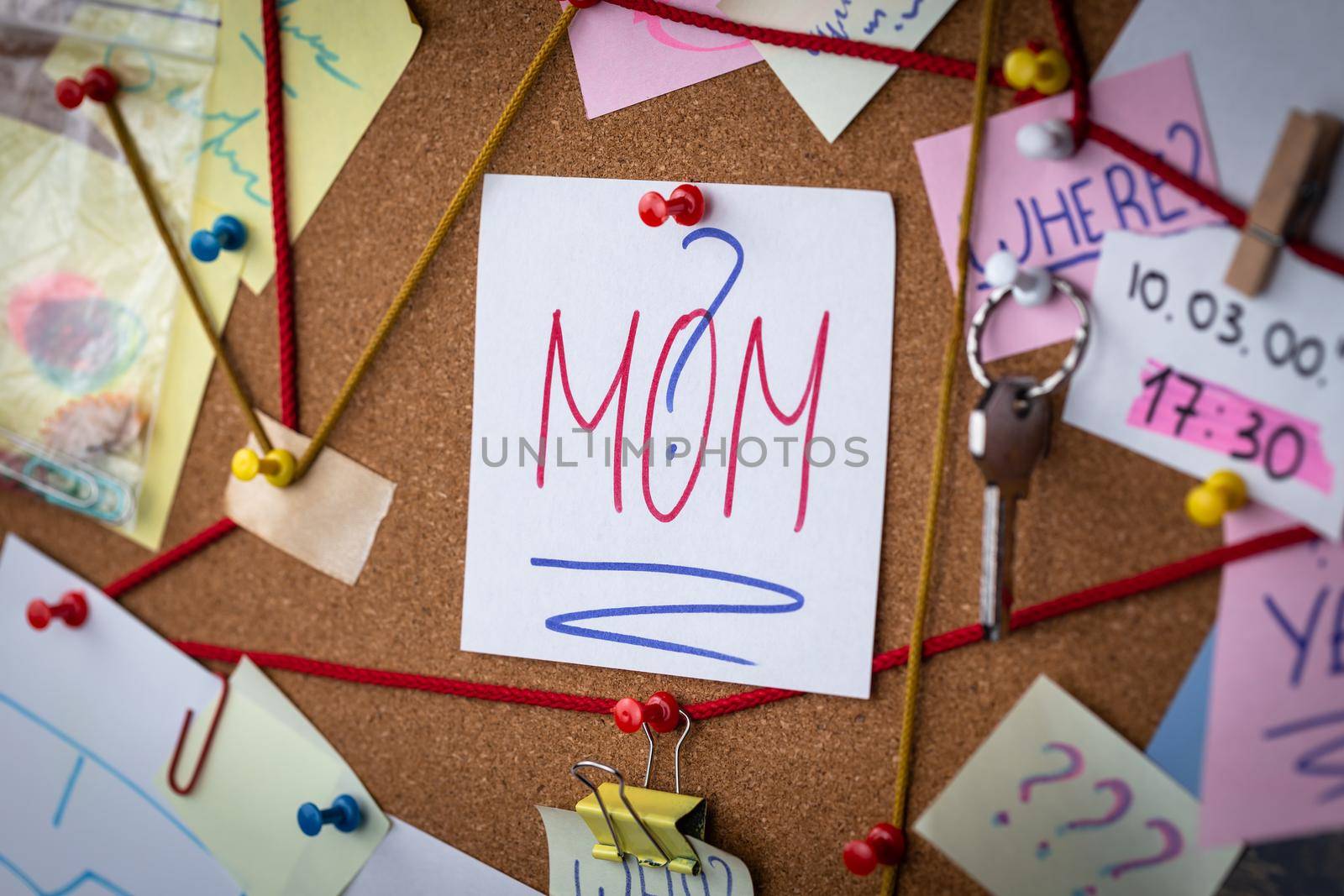 Mom search concept. Close-up view of a detective board with evidence. In the center is a white sheet attached with a red pin with the text Mom.