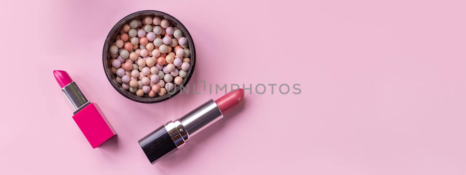 Decorative cosmetics and accessories for make up on pink background.Composition of cosmetics with pink lipsticks and ball blush.Various cosmetic products for make-up. Copy space by YuliaYaspe1979
