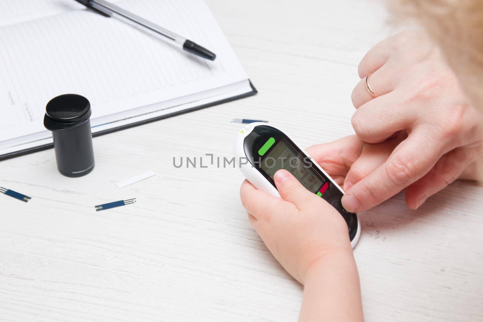 a small child holds a glucose meter, a woman helps her measure blood sugar, childhood diabetes, control and sugar test