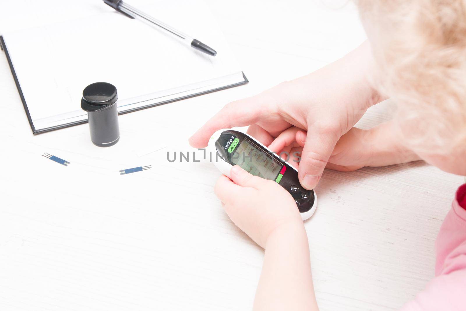 an elderly woman helps a child to measure blood sugar, glucose meter, diabetes mellitus concept