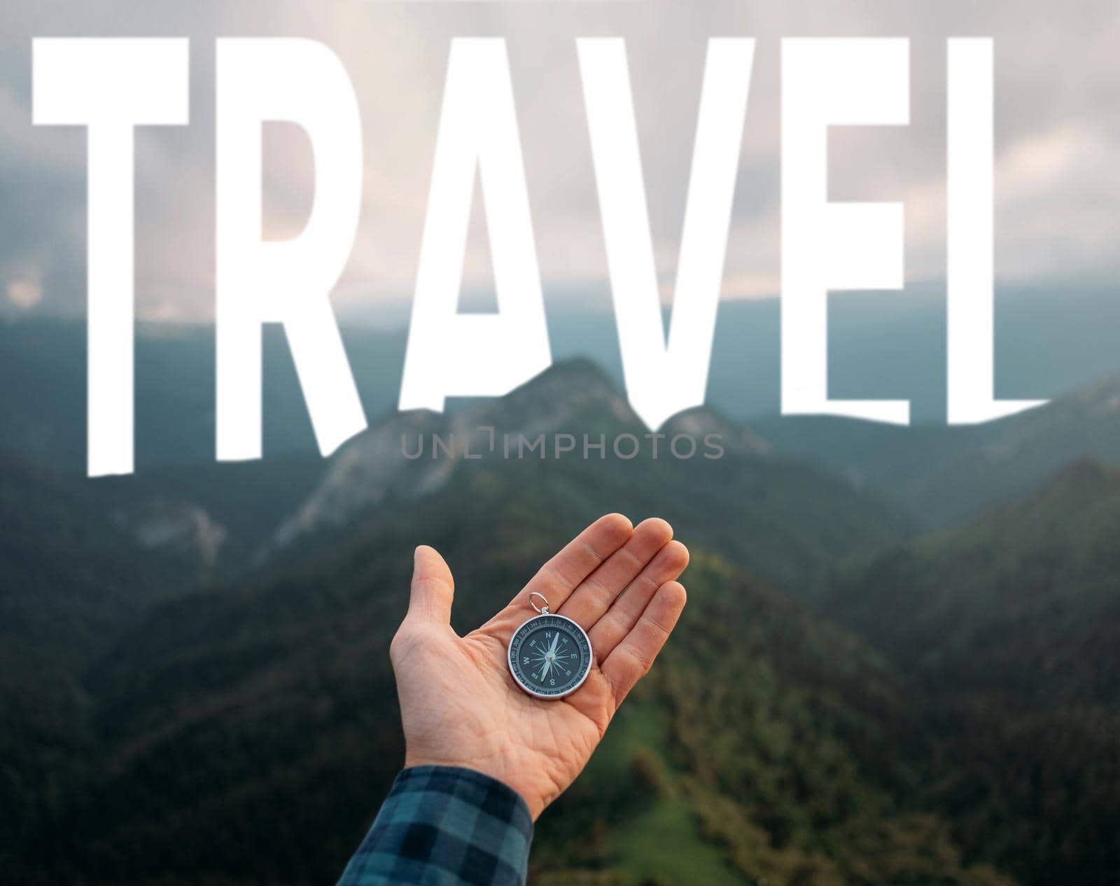 Male hand with compass on background of mountains and word travel in the sky, point of view in first person.