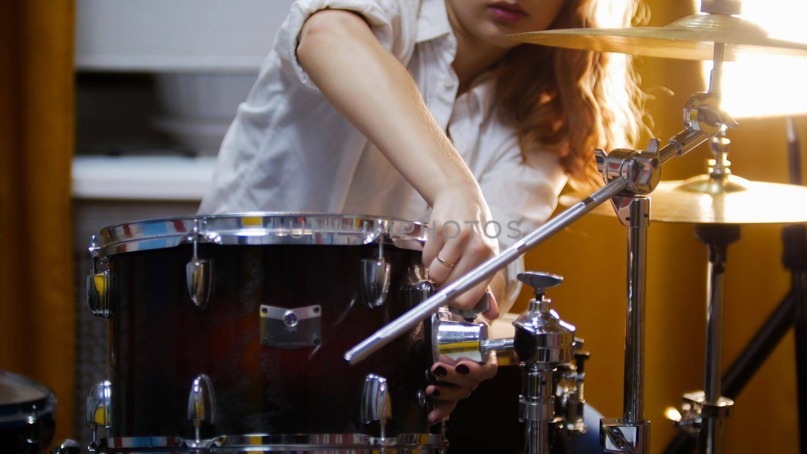 Repetition. Ginger girl plays drums raid. The girl fixing snare. Studio