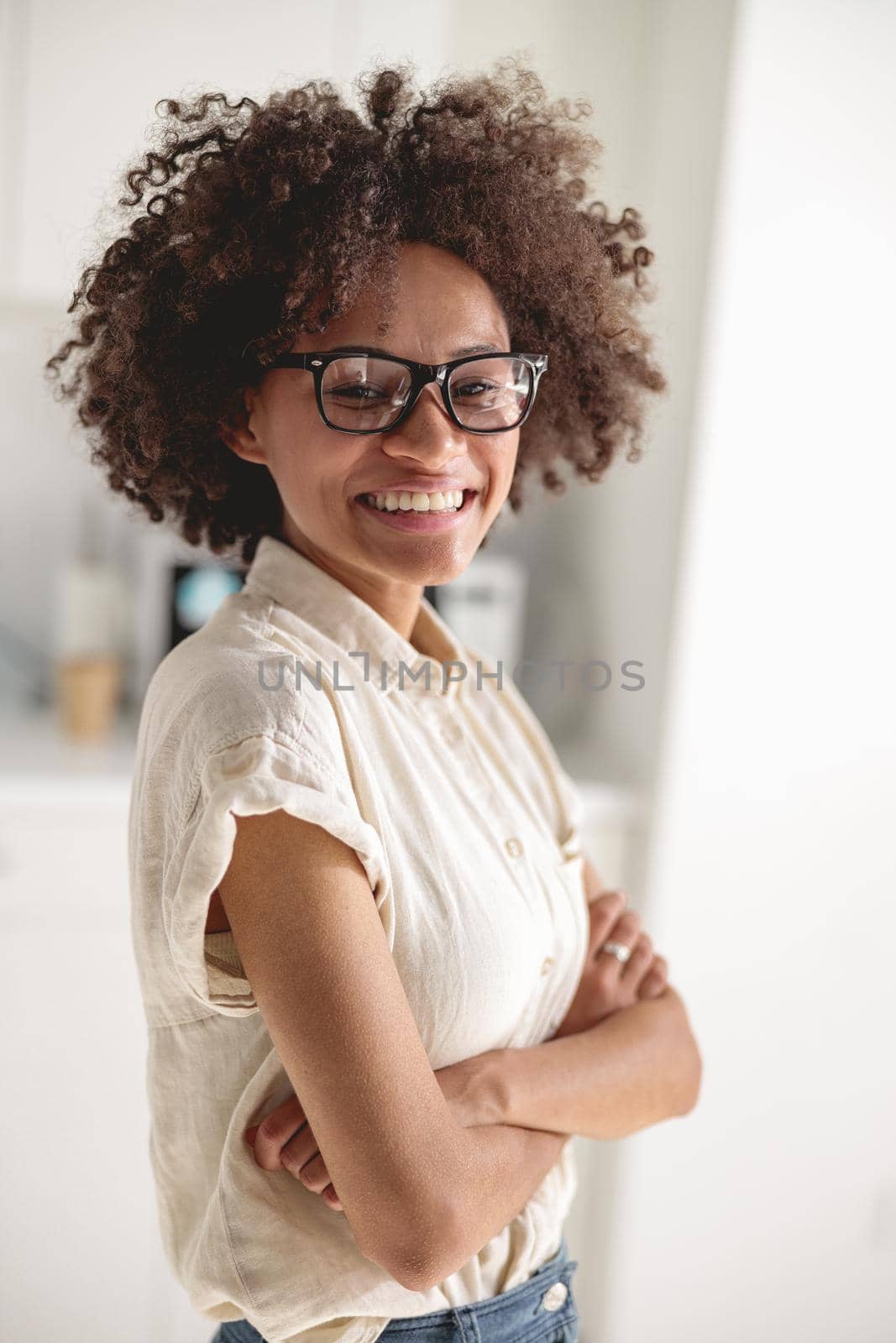 Portrait of smiling Afro American lady with arms folded standing in office and looking at camera