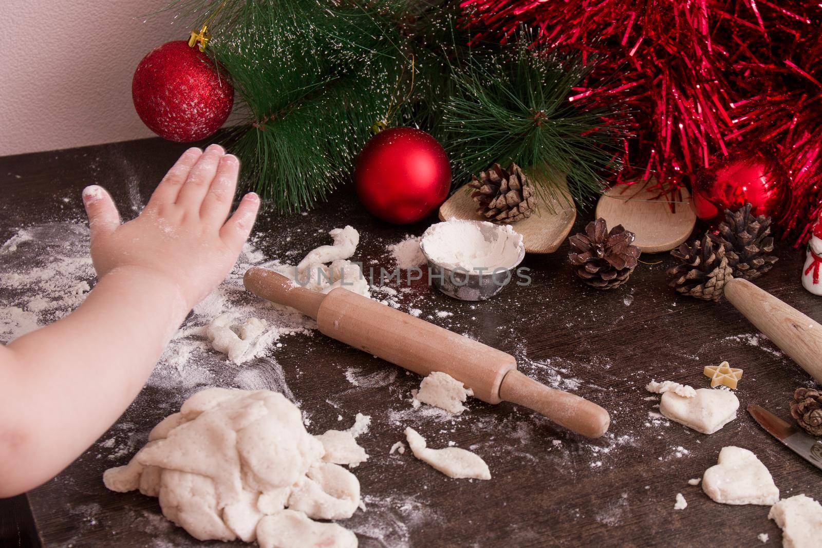 little girl's hand makes christmas cookies, christmas background, bright colors, red christmas tree decorations, copy space