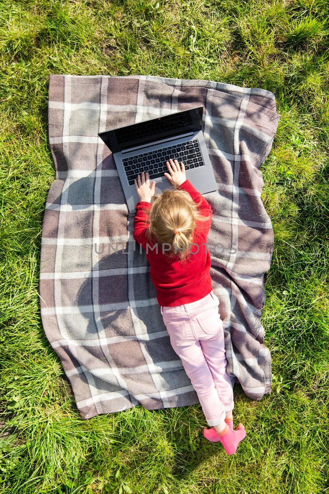 Child girl playing on a laptop in the garden. by esvetleishaya