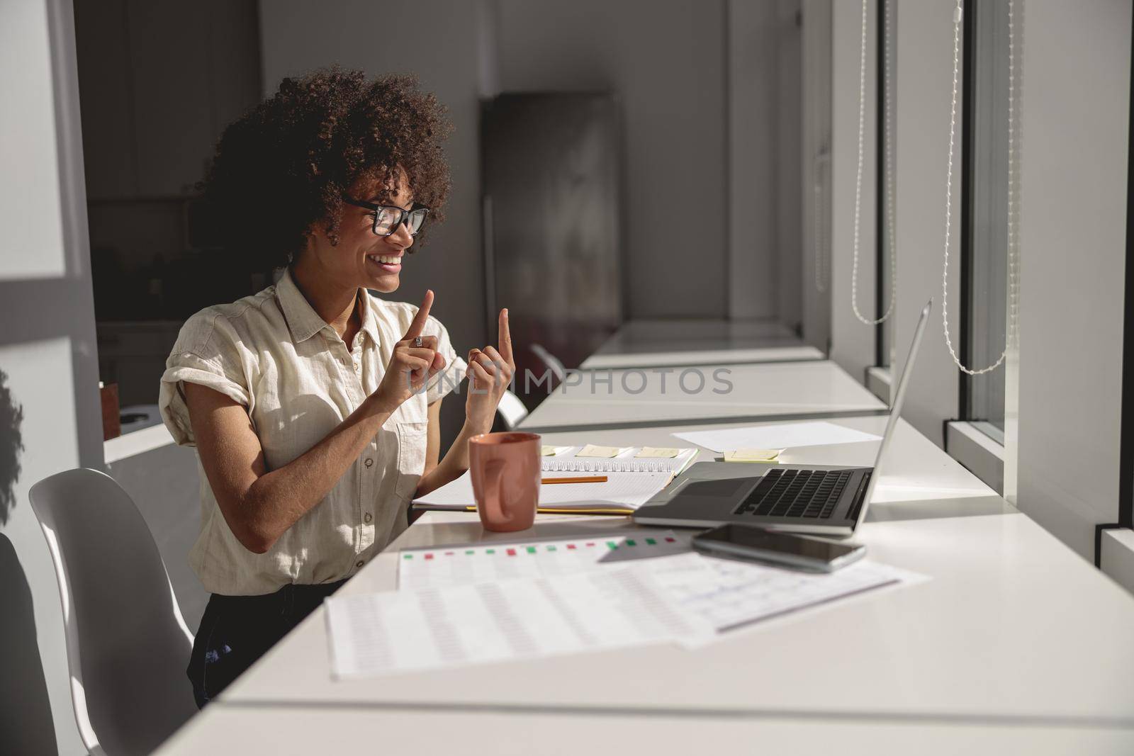 Happy pretty lady learning and communicating in sign language online while sitting in the office