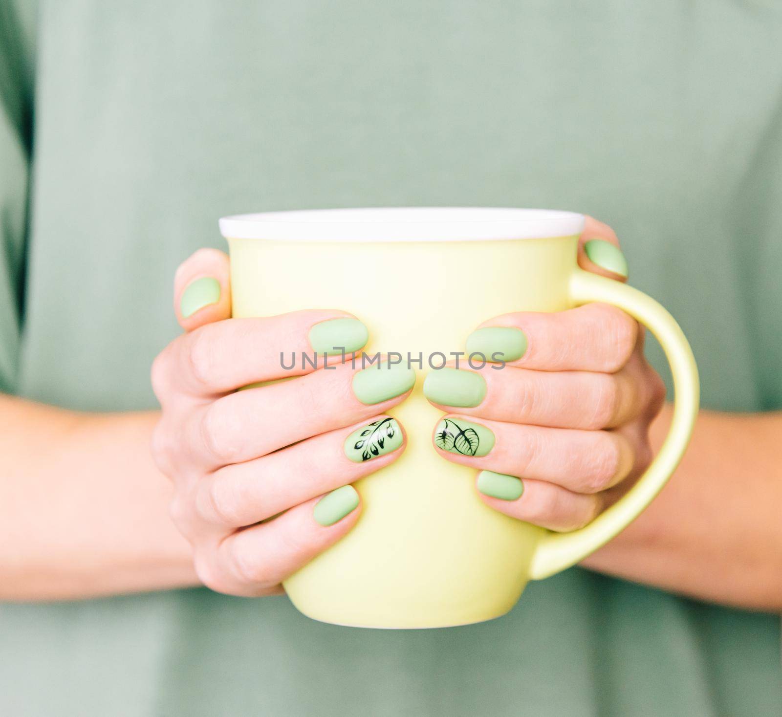 Female hands with trendy summer stylish green manicure holding a cup. by alexAleksei