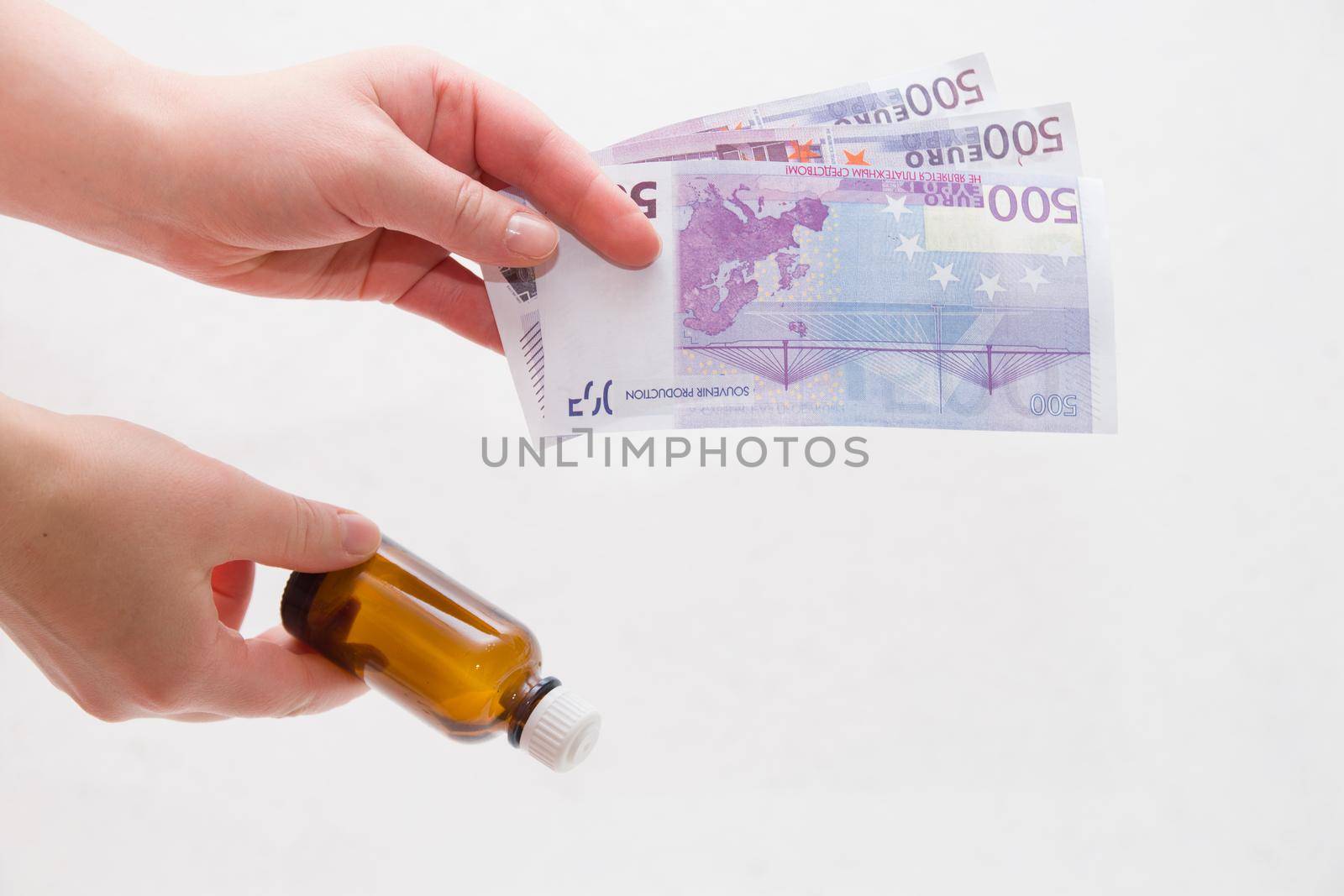 female hands holding a bottle of medicine and euro notes on a white background