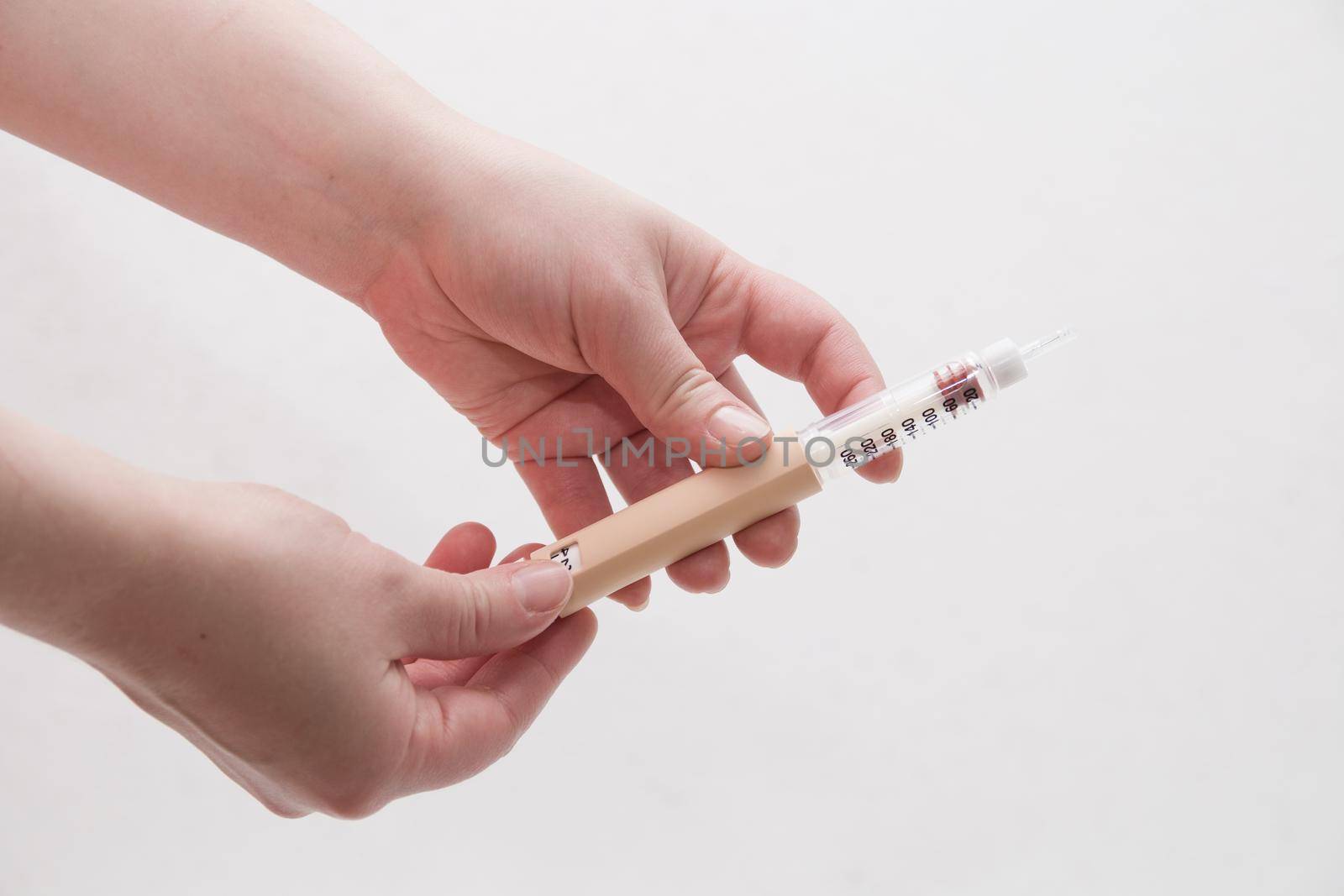 female hands holding a syringe a pen for insulin injection to a patient with diabetes white background by natashko