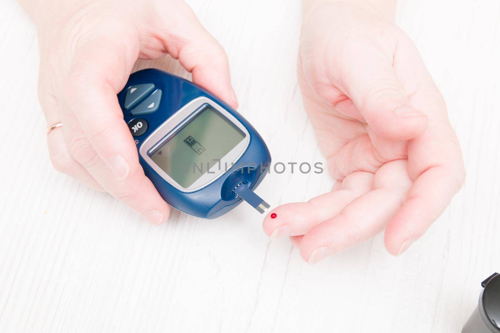 female hands measure blood sugar, a drop of blood on the finger and glucose meter, diabetic do blood test, diabetes concept